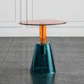 Modern side table with a transparent glass top and teal base on a gray floor, Obroi