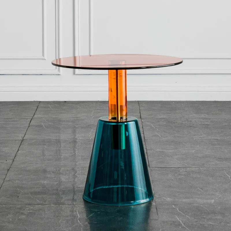 Modern side table with a transparent glass top and teal base on a gray floor, Obroi