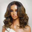 A shoulder-length wavy wig with a dark brown root and warm caramel-to-blonde highlights, styled on a mannequin head against a light gray background, Obroi