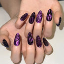 Hand with purple and black zebra-striped nail design on a neutral background