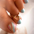 Close-up of a hand with colorful nail art and a gold ring, Obroi