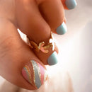 Close-up of a hand with colorful nail art and a gold ring, Obroi