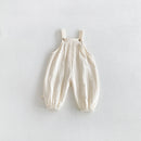 Cream-colored crinkle cotton baby overalls with adjustable shoulder straps and elasticized leg cuffs, laid flat on a light gray background, Obroi