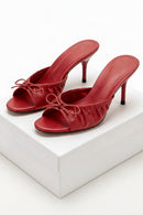 Red high-heeled shoes with bow details on a white background, Obroi