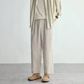 Person wearing beige pants and a striped shirt against a plain background, Obroi
