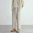 Person wearing beige pants and a striped shirt against a plain background, Obroi