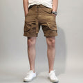 Person wearing brown cargo shorts and white sneakers against a white background, Obroi
