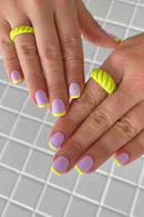 Close-up of hands with pink and yellow nail polish on a grid background, Obroi