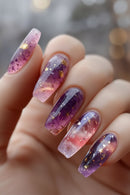 Hand with purple and pink galaxy-themed nail art on a blurred background, Obroi