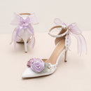 White high-heeled shoes with floral decorations and ribbons on a light background, Obroi