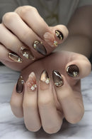 Close-up of hands with decorative nail art featuring gold and brown tones, Obroi