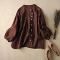 Brown blouse with long sleeves on a beige surface with shoes and dried plants, Obroi