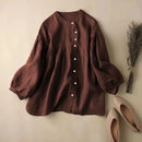 Brown blouse with long sleeves on a beige surface with shoes and dried plants, Obroi