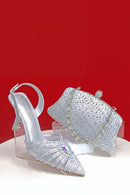 Silver high-heeled shoes with matching headpiece on a red background, Obroi