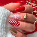 Hand with festive nail art featuring red, white, and gold designs on a red background, Obroi