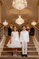 Two children in formal attire standing on a staircase in an elegant indoor setting, Obroi