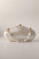 Pearl-handled clutch bag with gold accents on a light background, Obroi