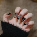 Obroi Hand with black and silver nail art on a blurred background