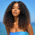 A woman wearing a Obroi curly hair extension with dark brown to black finger coil ends, set against a blue ocean background. An inset in the bottom right corner shows a close-up of the hair texture, Obroi
