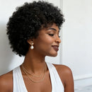 Woman with styled hair wearing a white top and gold jewelry against a neutral background, Obroi