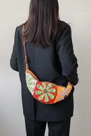 Person wearing a colorful crochet bag with a plain background, Obroi