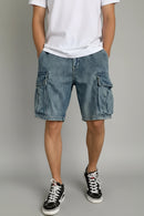Person wearing blue cargo shorts and black sneakers on a gray background, Obroi