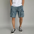Person wearing blue cargo shorts and black sneakers on a gray background, Obroi