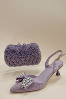 Purple high-heeled shoe with decorative bow and matching clutch on a white background, Obroi