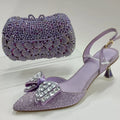 Purple high-heeled shoe with decorative bow and matching clutch on a white background, Obroi