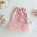 Pink dress with a bow and ruffles on a light gray surface, surrounded by shoes and a teddy bear, Obroi