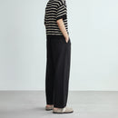 Person wearing black wide-leg pants and a light-colored top on a plain background, Obroi