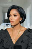 Woman with styled hair wearing a black top and gold necklace indoors, Obroi