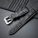 Black leather watch strap with silver buckle on a dark gray background, Obroi