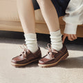 Brown leather shoes worn with white socks on a neutral background, Obroi