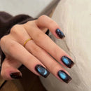 Hand with dark nail polish and a gold ring on a neutral background, Obroi