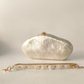 White clutch bag with gold chain on a light gray background, Obroi