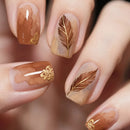 Nails with brown nail polish and gold feather designs on a blurred background, Obroi