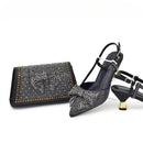 Black studded high-heeled shoes with a matching clutch on a white background, Obroi