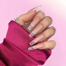 Hand with decorative nail art on a pink background, Obroi