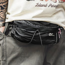 Person wearing a black waist bag with visible branding on a neutral background, Obroi