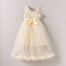 A baby girl's one-shoulder tulle dress in cream and pale yellow, featuring a textured knit bodice, a large bow at the waist, and a fluffy ruffled hem, shown against a neutral gray background, Obroi