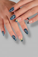 Close-up of hands with blue nail art on a book page background, Obroi