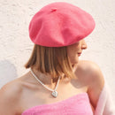 Woman wearing a pink beret and pink top against a light background, Obroi