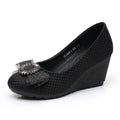 A single women's black wedge pump shoe with a textured woven upper and a decorative black mesh bow embellished with silver rhinestones on the toe, shown against a plain white background, Obroi