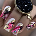 Nails with pink, gold, and black design, held by a hand wearing a gold ring, Obroi