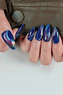 Close-up of a hand with blue and purple gradient nail polish against a neutral background, Obroi