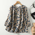 Floral patterned blouse on a hanger with shoes and a handbag in the background.