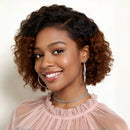 Woman with curly hair wearing a pink top and hoop earrings on a plain background, Obroi