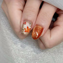 Close-up of a hand with autumn-themed nail art on a textured gray background, Obroi