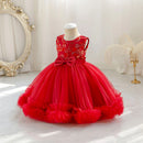A bright red toddler girl's party dress displayed on a mannequin. The sleeveless dress features a floral embroidered bodice, a matching red satin waistband with a large bow, and a voluminous tiered tulle skirt with ruffled trim, Obroi